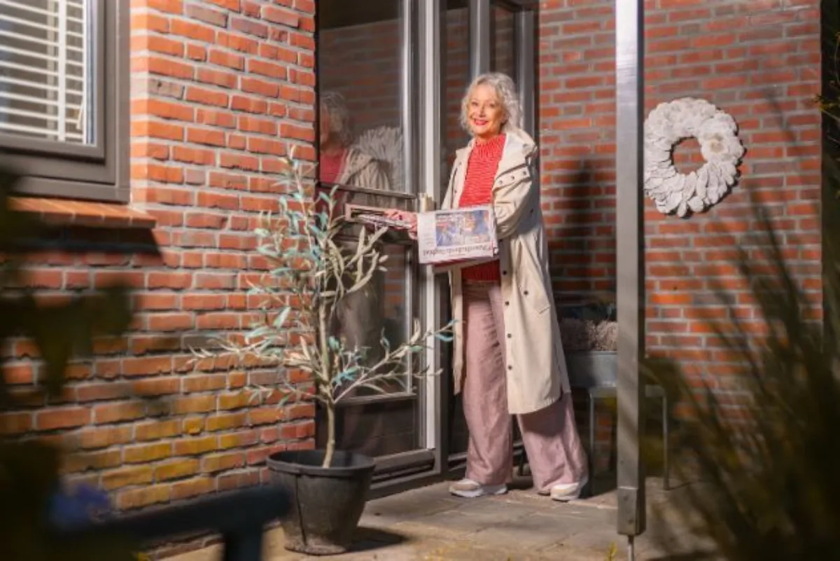 Slider image Krantenbezorgster stopt krant in brievenbus