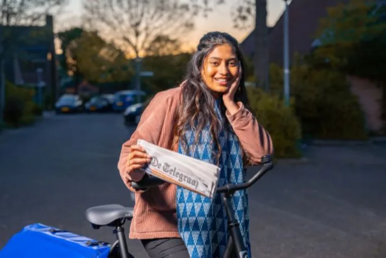 Slider image Krantenbezorgster houdt krant vast
