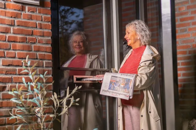 Content image Krantenbezorgster die een krant in de brievenbus stopt
