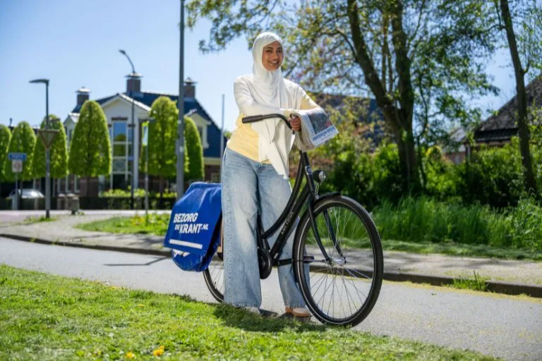 Content image krantenbezorgster bezorgt de krant op haar fiets